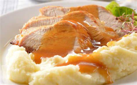 Pechuga de pavo en salsa de queso servida con puré de papas y una ensalada fresca