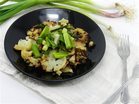 Coliflor y ajos tiernos fritos en una sartén