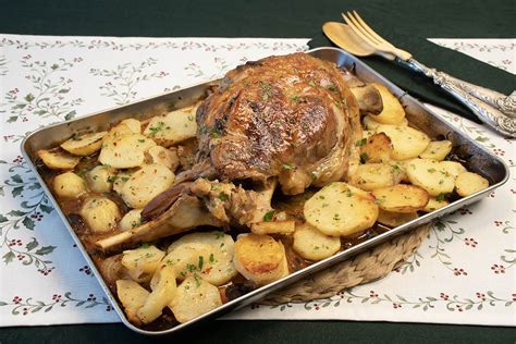 Pierna de cordero asada con patatas panadera en una bandeja de horno