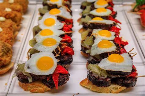 Montaje de pincho de morcilla con huevo y pimientos