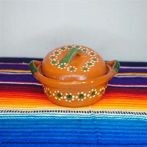 Variedad de cazuelas ovaladas y redondas de barro sobre una mesa de madera