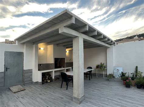 Barbacoa de obra con una pérgola de aluminio a su lado