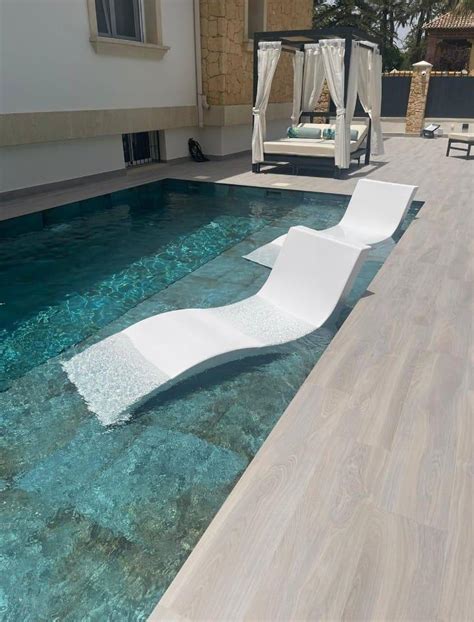 Piscina exterior de temporada con tumbonas y vistas al campo