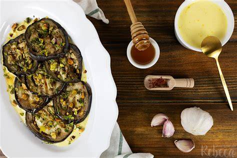 Plato de berenjenas con salsa de ajo y azafrán, decorado con pistachos y perejil