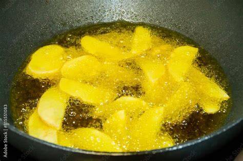 Patatas y cebolla pochándose en una sartén