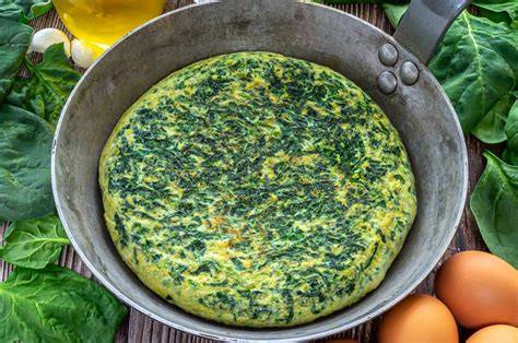 Tortilla de patatas y espinacas cocinándose en la sartén