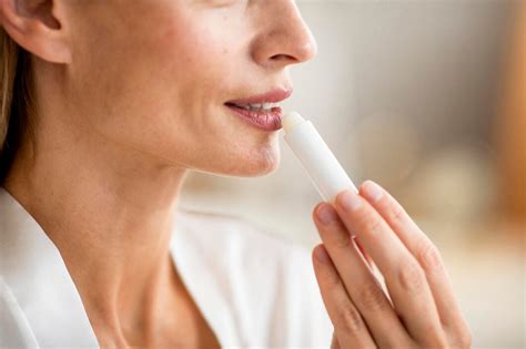 Persona aplicando bálsamo en sus labios y nariz