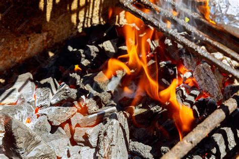 Parrilla con carbón encendido y llamas controladas