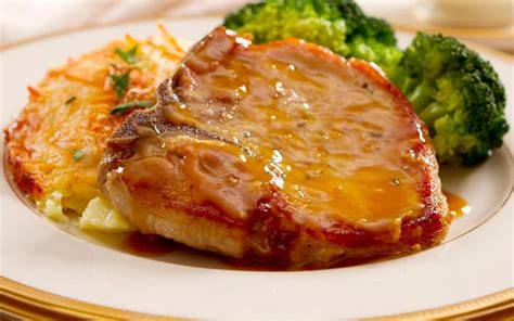 Plato de chuletas de cerdo con salsa de cebolla servido con guarnición
