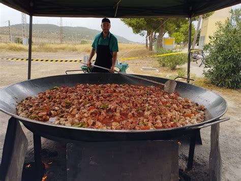 Personas cocinando paellas en un evento al aire libre