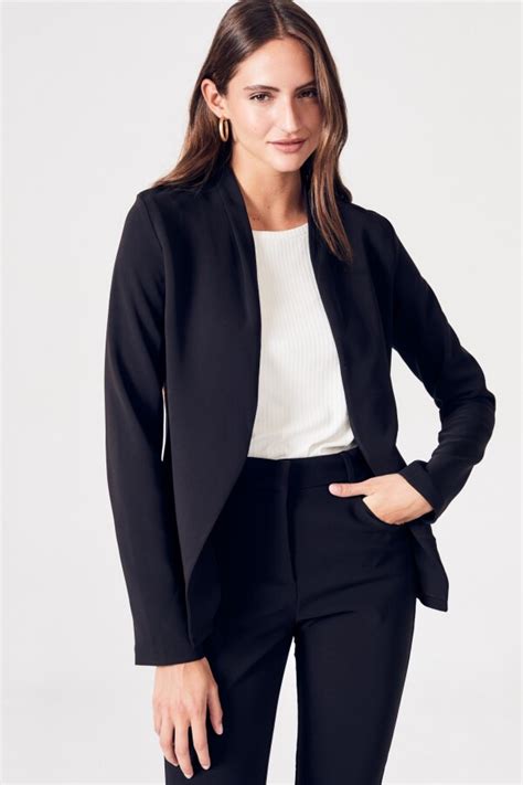 Mujer en un ambiente de oficina luciendo un blazer negro con un vestido midi satinado