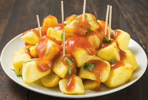 Patatas bravas servidas en un plato con un tazón de salsa brava