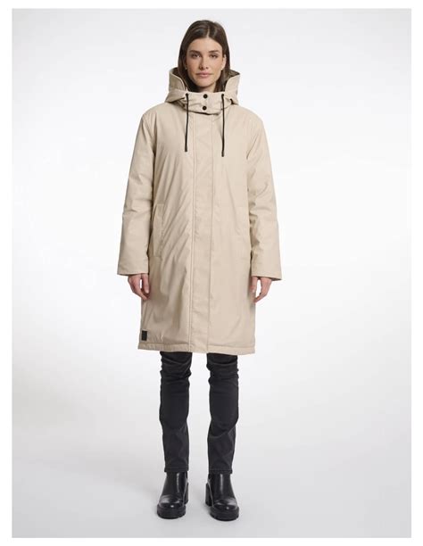 Mujer usando una parka Burton color tostado en un paisaje urbano