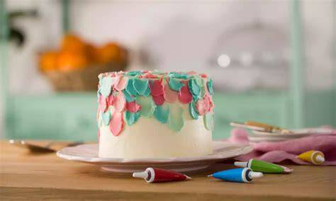 Bizcocho decorado con nata verde y detalles de lápices pasteleros