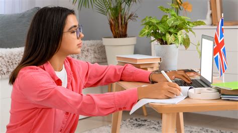 Persona estudiando inglés con un libro y un ordenador, mostrando concentración