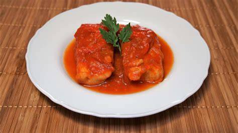 pescado dispuesto en una bandeja de horno con salsa de tomate y verduras