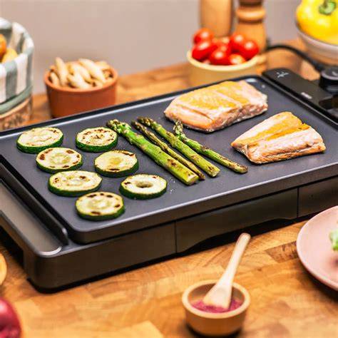 Plancha de asar en uso, mostrando diferentes alimentos cocinándose