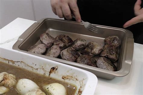 Carrilleras de cerdo asadas con patatas y cebolla en una bandeja de horno