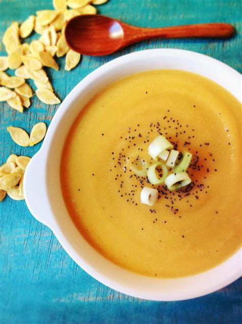 Fotografía de un bol con crema de lentejas rojas y calabaza, decorada con semillas y picatostes.