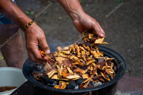 Persona añadiendo astillas de madera aromáticas a las brasas de carbón