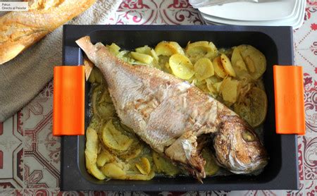 Pescado asado en el horno sobre una cama de patatas y cebolla