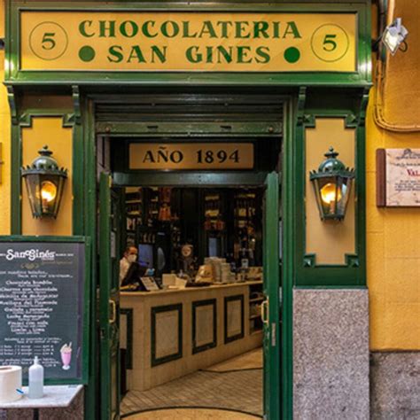 Interior de la Chocolatería San Ginés con mesas de mármol y azulejos