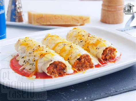 Canelones rellenos cubiertos con bechamel y queso listos para gratinar