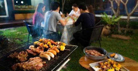 Familia y amigos reunidos alrededor de una parrilla para una carne asada
