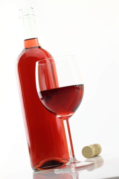 Botella de vino rosado y copa junto al plato de lentejas con calamares