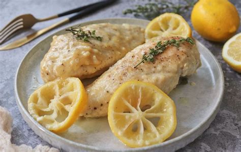 Pechugas de pollo crudas en un plato con limón y hierbas