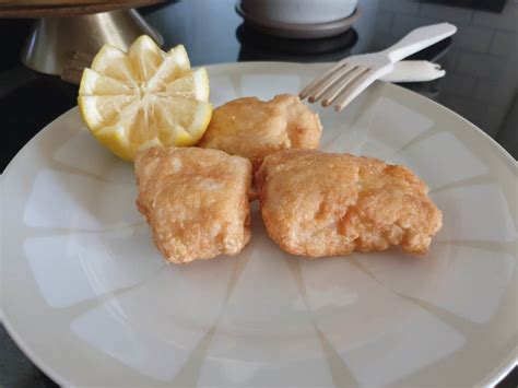 Merluza rebozada tradicional dorada en un plato con limón