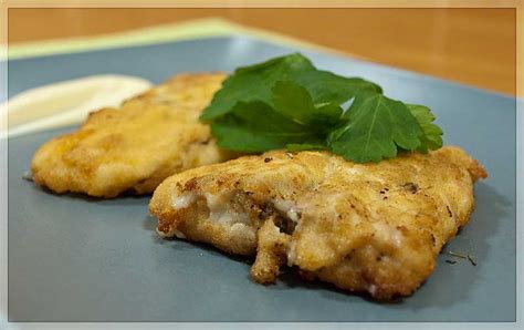 Merluza rebozada en bechamel con queso azul servida en una fuente
