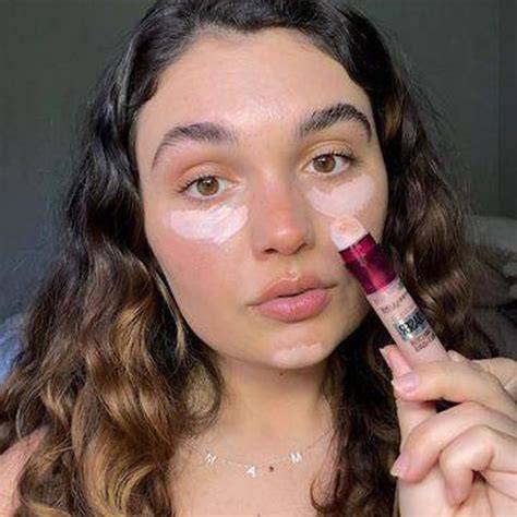 Mujer aplicando corrector de ojeras con una brocha