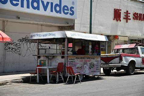 Mujeres latinas siendo filmadas en un puesto de comida ambulante