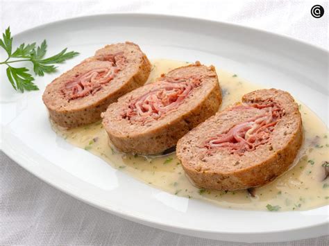 Plato servido de rollo de carne con salsa y guarnición