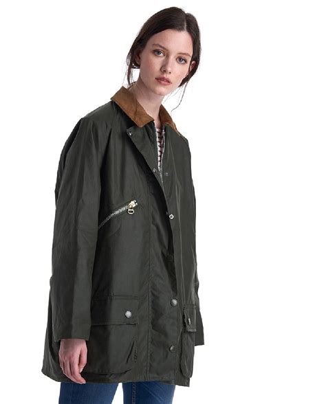 Mujer con parka encerada verde y cuello de pana paseando por el campo en otoño