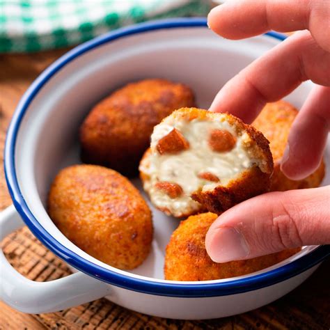 Imagen de un plato de croquetas de chistorra y queso recién fritas, acompañadas de una ensalada
