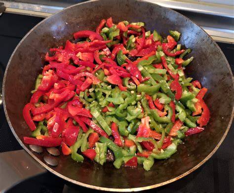 Pimientos y cebolla pochándose en una sartén