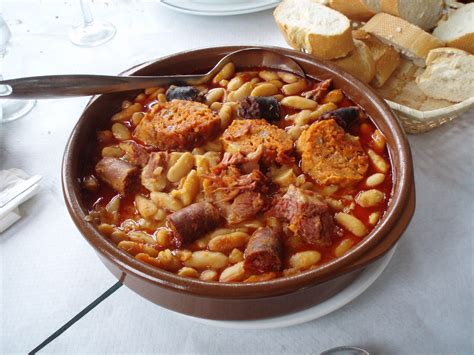 Plato tradicional de fabada asturiana humeante en cazuela de barro