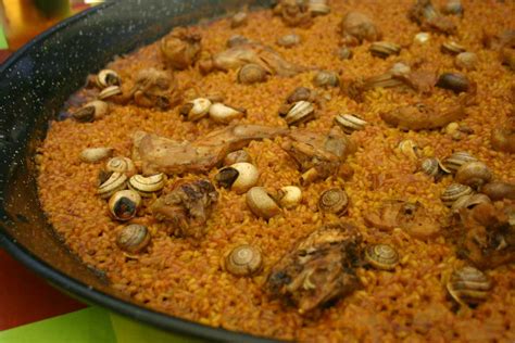 Paella de conejo y caracoles cocinándose a leña