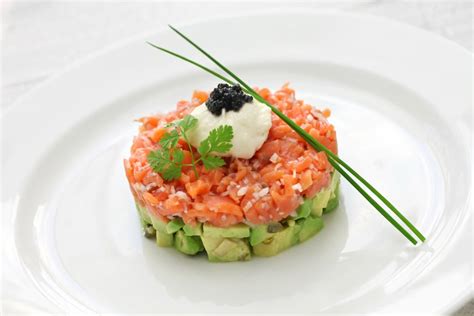 Tartar de salmón con aguacate servido en plato elegante