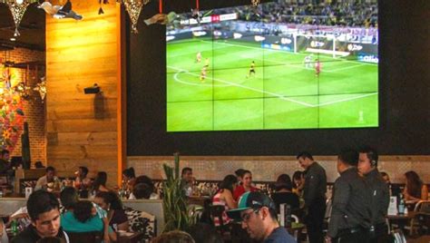 Interior de Sports Grill con pantallas transmitiendo eventos deportivos.