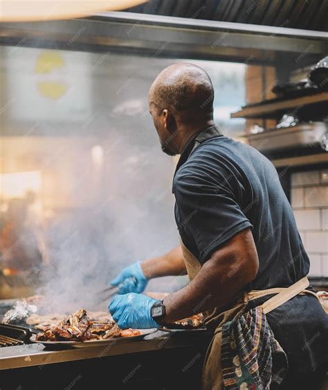 Parrillero experto asando diferentes cortes de carne en una parrilla de carbón