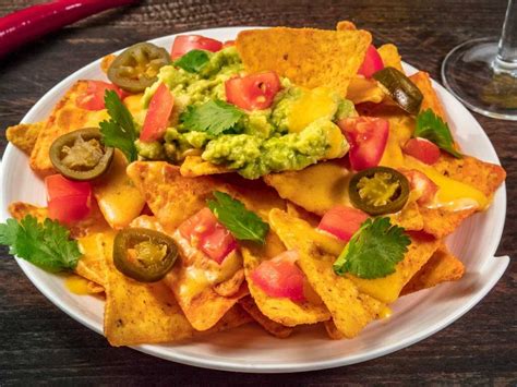 Plato de nachos con salsa de queso cheddar, jamón, bacon y jalapeños