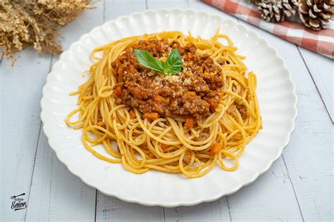 Espagueti a la boloñesa servido con albahaca y queso