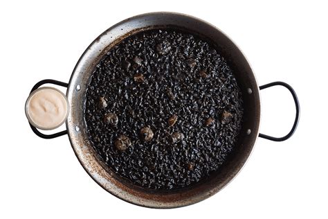 Hermanos Torres preparando arroz negro en una paellera grande