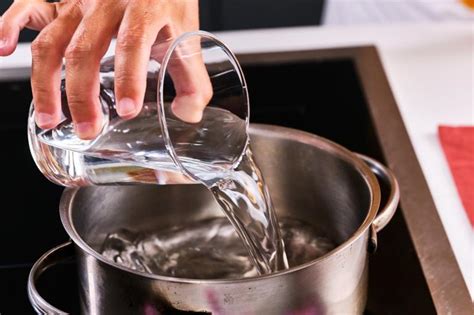 Manos añadiendo agua fría a una cazuela de alubias hirviendo