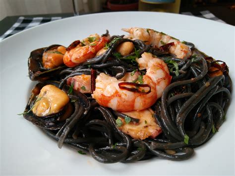 Plato de espagueti al nero di sepia con salmón y gambas