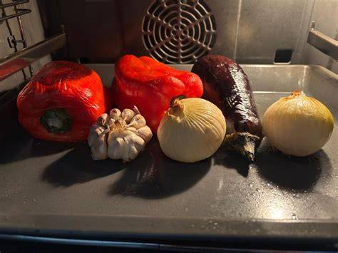 Tomates y verduras asándose en una bandeja de horno