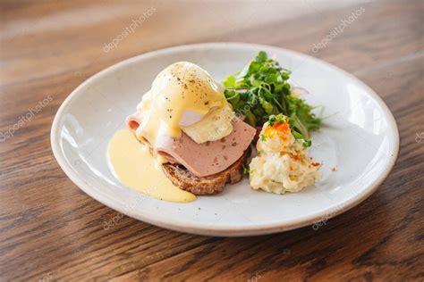 Plato de huevos Benedict con jamón y pan